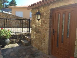 Casa de piedra con puerta de madera y valla en Casa Ruso, en Os Muinos