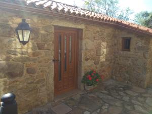 a stone house with a wooden door and a potted plant at Casa Ruso in Os Muinos