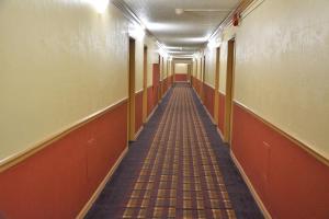 an empty hallway with orange walls and a long aisle at Columbus Grand Hotel & Banquet Center in Worthington +26 photos
