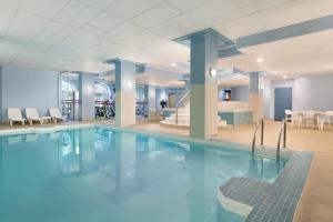 a swimming pool in a hotel with chairs and tables at Coast Edmonton Plaza Hotel by APA in Edmonton