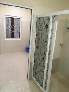 La salle de bains est pourvue d'une porte de douche et d'une fenêtre. dans l'établissement Uthayam, à Point Pedro