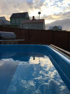 a blue swimming pool with a reflection of the sky at Garður restored house in Stykkishólmur