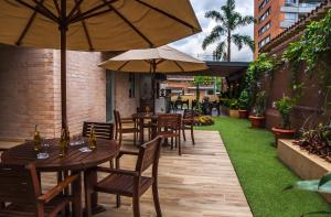 um pátio exterior com mesas e cadeiras com guarda-sóis em Hotel Lomas 10 em Medellín
