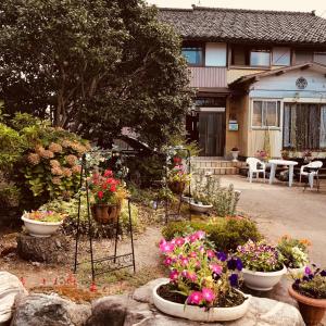 einen Garten mit Blumen in Töpfen vor einem Haus in der Unterkunft Kizuna no Ie in Uozu