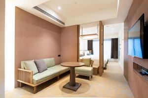 a hotel room with a couch and a table and a bed at Caesar Metro Taipei in Taipei