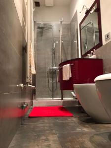 La salle de bains est pourvue d'une douche et d'un tapis rouge. dans l'établissement Nonna Anna, à Sienne