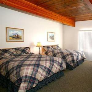 a bedroom with two beds and a wooden ceiling at Trails End Motel Sheridan in Sheridan +18 photos