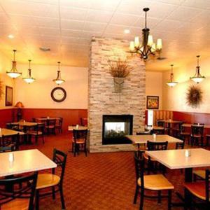 a restaurant with tables and chairs and a fireplace at Trails End Motel Sheridan in Sheridan