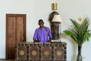 a man is standing at a table with a table at Tikitam Palms Boutique Hotel in Pongwe