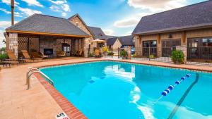 a swimming pool in front of a house at Best Western Plus Weatherford in Weatherford