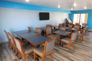 a waiting room with tables and chairs and a flat screen tv at Days Inn by Wyndham Oklahoma City NW Expressway in Warr Acres
