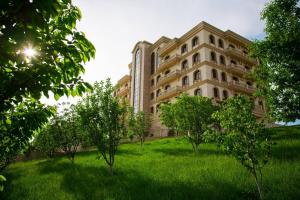 duży budynek z drzewami przed nim w obiekcie Kainar Hotel w mieście Szymkent