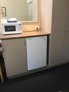
a kitchen counter with a microwave and a cupboard at The Bakehouse Motel in Goulburn
