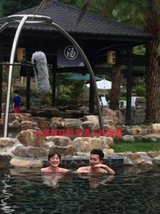 two people in a swimming pool with a waterfall at Song Hua Ju B&B in Heping
