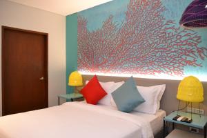 a bedroom with a bed with a painting on the wall at Lagùn Hotel in El Nido