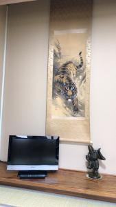 une télévision sur une étagère avec une photo d'un tigre dans l'établissement Minshuku Ginmatsu, à Kanazawa