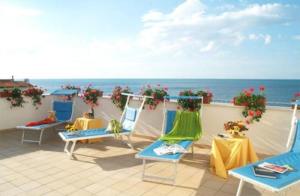 a balcony with chairs and tables and the ocean at Villa Nettuno in San Menaio