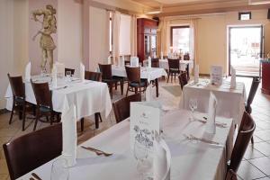 a restaurant with white tables and chairs and a statue at Hotel Zamojski in Zamość