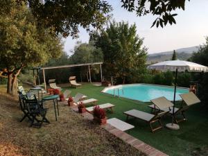 una piscina con tavoli, sedie e ombrellone di Villa Sant'Alberto a Monteroni dʼArbia