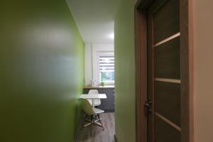 Zimmer mit grünen Wänden, einem Tisch und einer Tür in der Unterkunft Modern & Homely Apartment - FREE PARKING - NETFLIX in Kaunas