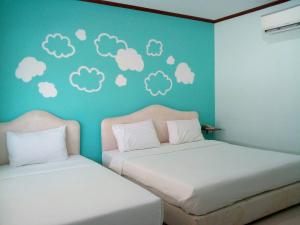 2 camas en una habitación con nubes en la pared en A Nice Resort, en Buriram