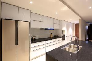 a kitchen with white cabinets and a stainless steel refrigerator at Golden Sun Apartment -Two bedrooms, Three bedrooms in Christchurch