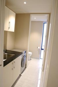 a kitchen with a washer and a sink and a washing machine at Golden Sun Apartment -Two bedrooms, Three bedrooms in Christchurch +6 photos