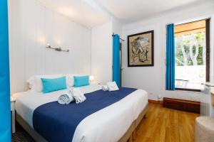 a bedroom with a large bed with blue pillows at Hôtel Les Liserons de Mougins in Mougins