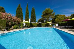 a swimming pool with chairs and umbrellas at Hôtel Les Liserons de Mougins in Mougins