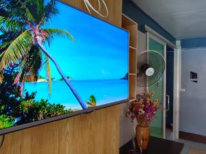 een flatscreen-tv in een kamer met een palmboom bij M Place in Ban Kao