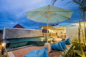 a pool with an umbrella and chairs and a patio at D'Yuki Huts Lembongan in Nusa Lembongan