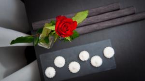 a red rose in a vase on a table with white cupcakes at Apartment City Lenaustrasse | contactless check-in in Hannover