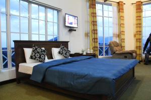 a bedroom with a bed with blue sheets and windows at Dewdrops at Lake Gregory in Nuwara Eliya