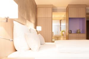 um quarto com uma cama branca e almofadas brancas em relexa hotel München em Munique