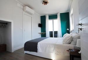 a bedroom with a white bed and a green wall at aquarium rooms in Genoa