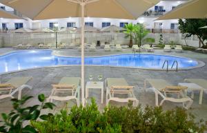 サロウにあるHotel Salou Beach by Pierre & Vacancesのホテルの前にテーブルとパラソル付きのプールがあります。
