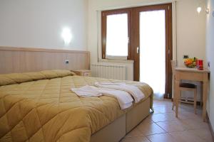 a bedroom with a bed and a desk and a window at Camere Rufino in Collestrada