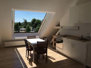 ハッティンゲンにあるBeautiful apartment in a historic villaのキッチン(テーブル、椅子付)、大きな窓が備わります。