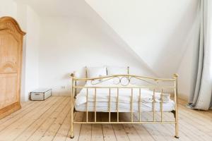 a white bedroom with a gold bed with white pillows at Beautiful apartment in a historic villa in Hattingen