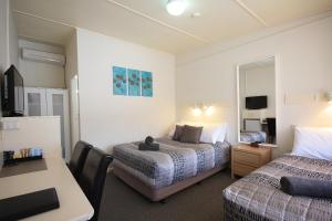 a hotel room with two beds and a desk at Hi Way Motor Inn in Yass