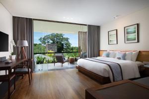 een hotelkamer met een bed, een bureau en een raam bij The Tamarind Resort - Nusa Lembongan in Nusa Lembongan