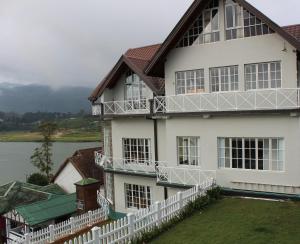 a large white house with a white fence at Dewdrops at Lake Gregory in Nuwara Eliya