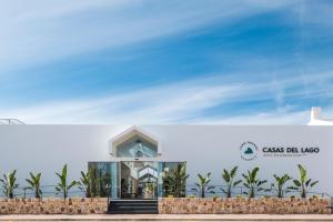 
a large white building with a sign on the side of it at Lago Resort Menorca - Casas del Lago Adults Only in Cala en Bosc
