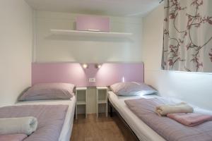 Duas camas num quarto com paredes cor-de-rosa e brancas em Camping Park Soline - Mendula I Mobile Home em Biograd na Moru
