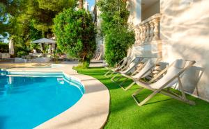 - un ensemble de chaises longues installées à côté de la piscine dans l'établissement Es Baulo Petit Hotel, à Can Picafort