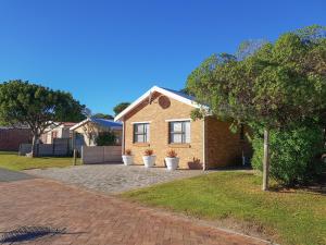 a brick house with potted plants on a driveway at Pearly Dunes in Pearly Beach