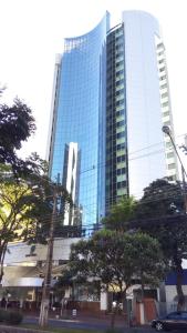 wysoki szklany budynek z drzewami przed nim w obiekcie Hotel Boulevard w mieście Londrina