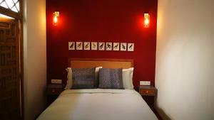 a bedroom with a bed with red walls and two lights at Dar Korsan in Rabat