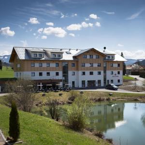 ein großes Gebäude mit einem Teich davor in der Unterkunft Chalet Alpenrose 134qm am Golfplatz Oberstaufen in Oberstaufen