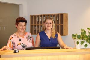 two women standing behind a counter with a laptop at Gästehaus - Kretschmannshof in Oberasbach